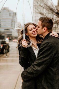 a man and woman standing under an umbrella in the rain on a city street together