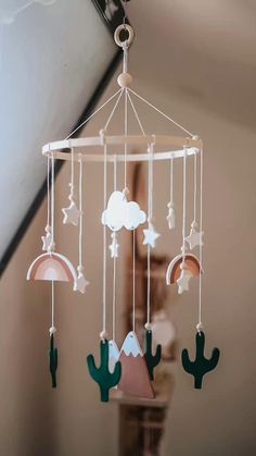 a mobile that is hanging from the ceiling with cactus decorations on it and stars, clouds, and crescents