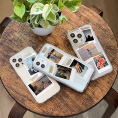 three cell phones sitting on top of a wooden table next to a potted plant