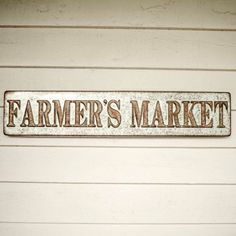 a metal sign that says farmer's market on the side of a building with white siding