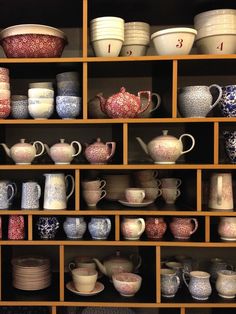 a shelf filled with lots of different types of dishes and cups on top of wooden shelves