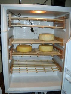 an open refrigerator filled with lots of cheeses and other food items on it's shelves