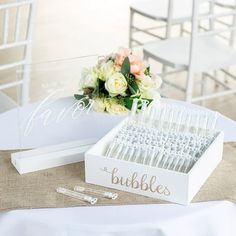 a table topped with lots of white flowers next to a box filled with plastic utensils