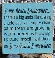 a blue sign sitting on top of a pile of rocks next to a basket filled with seashells