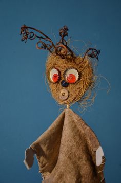 a bird's nest with buttons and wire attached to the top, against a blue background