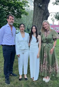 three people standing next to each other in front of a tree