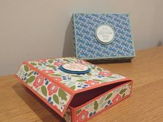 an open box sitting on top of a wooden table next to a blue and white box