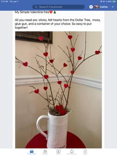 a white coffee cup with red hearts in it on a table next to a wall