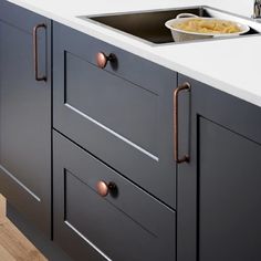 a kitchen sink sitting under a faucet next to a counter top with food on it