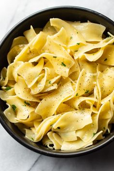 a black bowl filled with pasta on top of a table