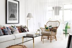 a living room filled with white furniture and lots of colorful pillows on top of it