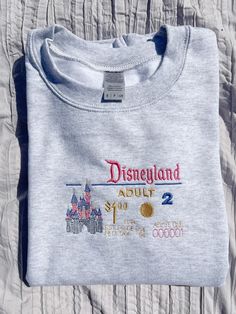 Item Description: Crewneck Featured in an ash color with embroidered Classic Disneyland ticket inspired design in pink blue and gold lettering . Perfect for a day at the park Gildan unisex pullover sweatshirt/Crewneck made out of 50/50 cotton and polyester blend. Size Recommendations: For women -True to size -For an oversized look size up one size For men -For relaxed look size up Recommended wash: -Machine wash cold -Inside out  -Tumble Dry Low Return Policy: -All sales are final. No returns, no exchanges due to t-shirts are being made to order, but please feel free to contact us for any problem or questions. Disneyland Shirt, Disneyland Tickets, Disneyland Shirts, Gold Lettering, Embroidered Crewneck, Sweatshirt Crewneck, Ash Color, Disney Outfits, Disney Trips