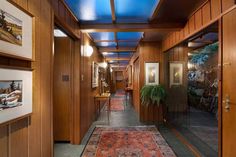 a long hallway with wood paneling and blue skylight above the doorway is lit by recessed lights