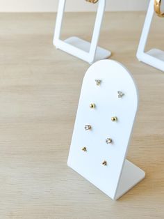 three pairs of gold and diamond earrings are on display in front of two white stands