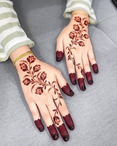 a woman's hands with hennap painted on them and red flowers in the middle