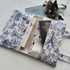 an open book sitting on top of a table next to a bouquet of flowers and books