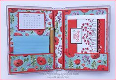 an open planner book with red flowers and blue paper on the pages, including a notepad