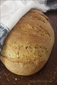 a loaf of bread sitting on top of a wooden table next to a white towel