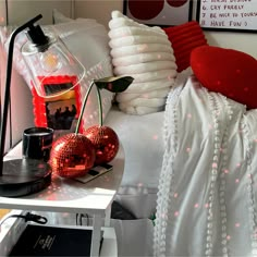 a bed with white sheets and red pillows on top of it next to a lamp