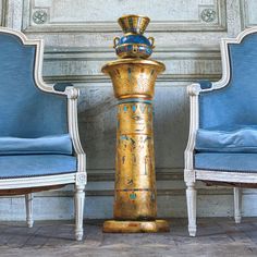 two chairs sitting next to each other in front of a table with a vase on it