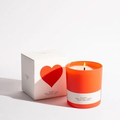 an orange candle sitting next to a box with a heart on the front and inside