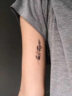 a woman's arm with a small flower tattoo on the left side of her right arm