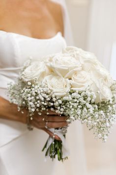 a bride holding a bouquet of white roses