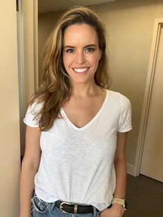 a woman standing in front of a door with her hand on her hip and smiling at the camera