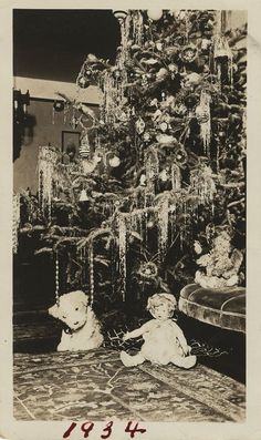 an old black and white photo of two teddy bears in front of a christmas tree