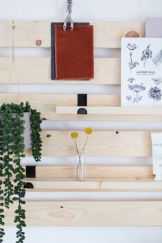 a wooden shelf with plants and other items hanging on it's sides, along with a notepad