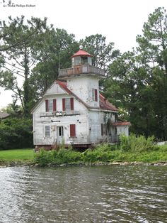 an old white house sitting on the side of a river