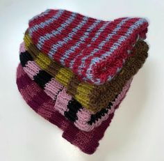 three knitted dishcloths stacked on top of each other in different colors and patterns