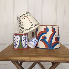 three ceramic cups sitting on top of a wooden table next to a light switch box