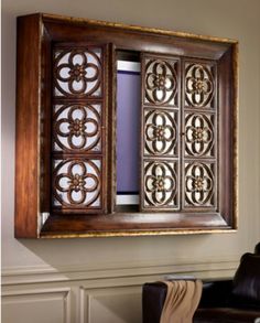 an ornate wooden frame hanging on the wall above a leather chair in a living room