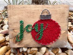 a red ornament with the word joy on it is sitting on some rocks