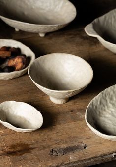 several white bowls and spoons sitting on a wooden table with dried fruit in them