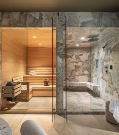 a bathroom with stone walls and a glass door that leads to the sauna room