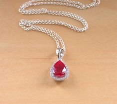 Sterling+silver+pendant+set+with+ruby+corundum+gemstone+with+crystal+zirconia+studded+surround.+This+beautiful+ruby+gemstone+is+created+in+laboratory+conditions+from+the+chemical+components+of+the+mineral+corundum+that+occur+in+the+natural+gemstone+ruby.+The+pendant+measures+1.4cm+length+x+1cm+wi... Ruby Jewellery, Pear Pendant, Ruby Necklace, Jewellery Uk, Classy Jewelry, Cz Pendant, Ruby Jewelry, July Birthstone, Ruby Gemstone