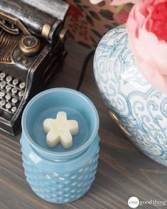 a blue candle holder sitting on top of a wooden table next to a typewriter