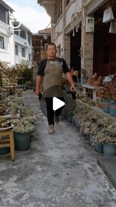 a man walking down a street next to lots of potted plants