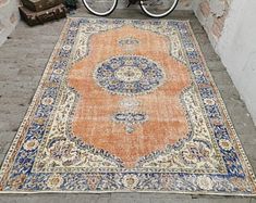 an orange and blue rug on the ground next to a bike