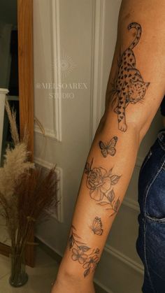 a woman's arm with tattoos on it and flowers in the middle, next to a mirror