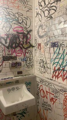 a bathroom with graffiti on the walls and a urinal next to it's sink