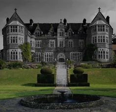 a large building with a fountain in front of it on a grassy area next to trees