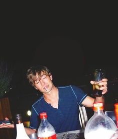 a man sitting at a table with bottles and drinks