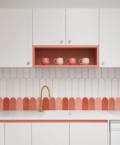 a kitchen with white cabinets and pink backsplash, gold faucet handles