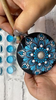 a person is painting something with blue and white designs on it while holding a pencil