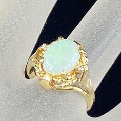 an opalite and diamond ring is displayed on a white surface with gold accents