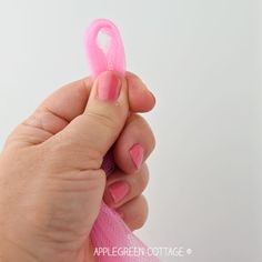 a person holding a pink ribbon in their hand