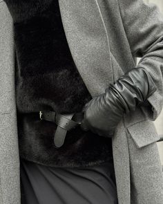 a person in a coat and leather gloves is holding their hand on his hip belt